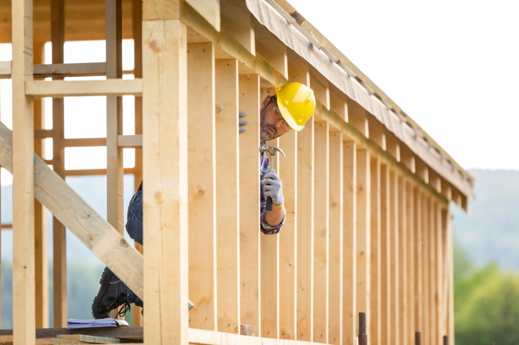 Builder working on wooden construction of frame house